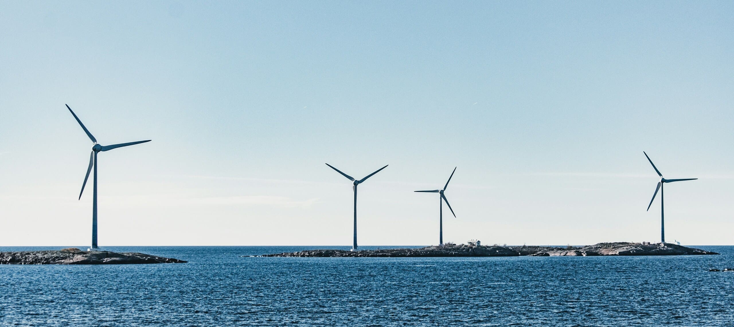 Offshore wind turbines standing in the sea against a clear blue sky